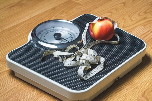 A scale with an apple and measuring tape.